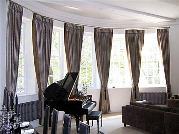 Large bay window with triple pleat curtains fitted to chrome poles